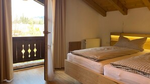 Une chambre avec deux lits, un plafond en bois, une fenêtre avec des rideaux et une vue sur la verdure.