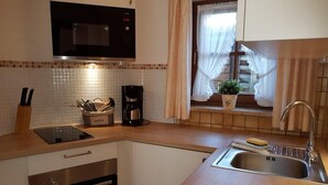 Une cuisine compacte équipée d’un four à micro-ondes, d’une machine à café et d’un évier.