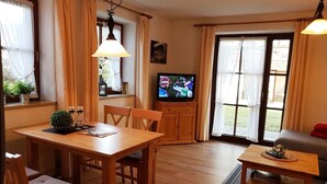 Un salon chaleureux avec une table à manger en bois, des chaises, un téléviseur et un canapé.
