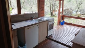 Una terraza de madera con zona de cocina que incluye un fregadero, estufa y lavavajillas.