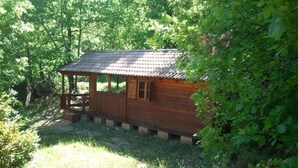 Una cabaña de madera con techo de tejas, rodeada de abundante vegetación.