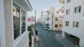 A narrow urban street with residential buildings on both sides, featuring balconies and satellite dishes.