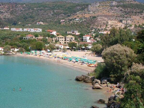 A coastal town with a beach, houses, and a rocky hillside. - Villa Phoebe in Stoupa, very quiet area, private pool, spectacular sea views. (Stoupa,)