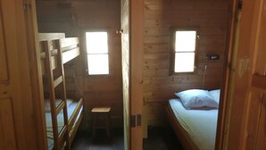 A small, wooden cabin room with bunk beds, a small stool, and two windows providing natural light. - Chalet Aiguebelle  (Simiane-la-Rotonde)