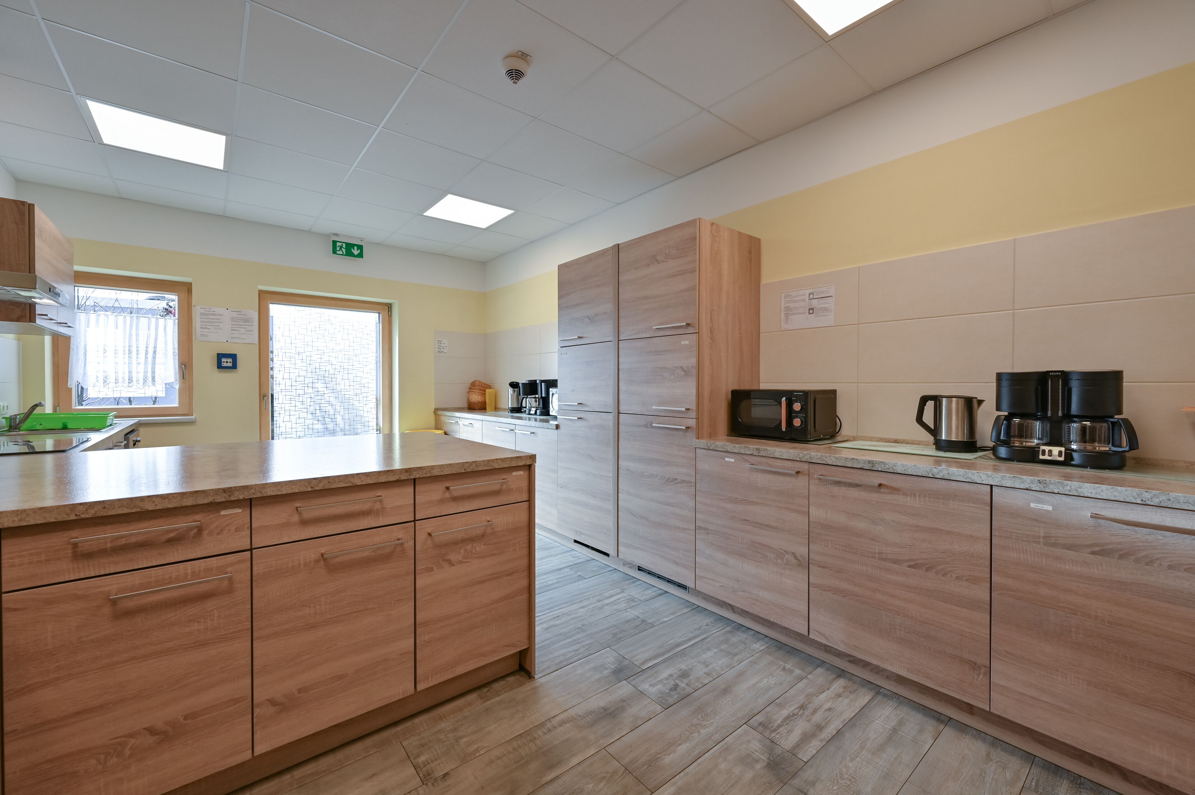 A modern kitchen with wooden cabinets, a large island, and a coffee maker.