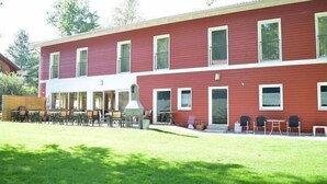 A red building with multiple windows and a covered outdoor seating area with tables and chairs.