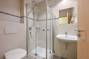 A modern bathroom with a glass-enclosed shower, a white sink, and a toilet.