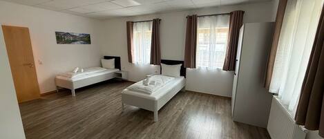 A room with a bed, a sofa, a desk, and a window with curtains.