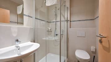 A modern bathroom with a glass-enclosed shower, a white sink, and a toilet.