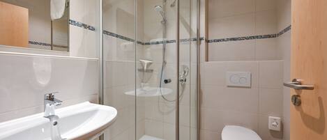 A modern bathroom with a glass-enclosed shower, a white sink, and a toilet.