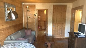 A cozy room with a sofa, a small table, a TV, and a wooden floor. - MEGEVE-T2-44M²-NEAR TOWN CENTER (Megève)