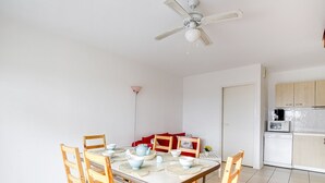 Zona de menjador amb taula rodona, cadires de fusta i un ventilador de sostre.