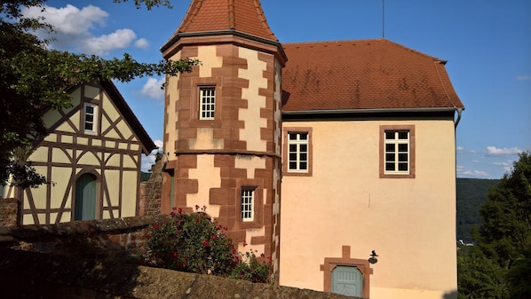 A traditional building with a tower and a main building, both featuring multiple windows and a stone facade.