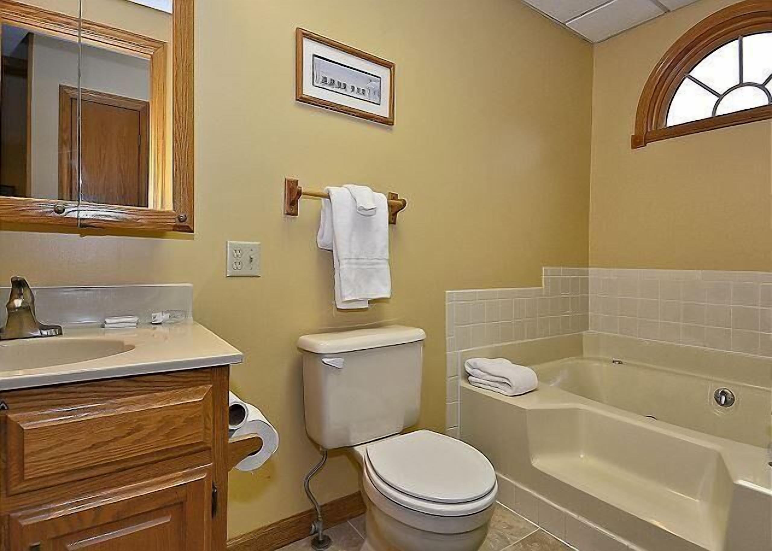 A bathroom with a toilet, sink, vanity, and bathtub.
