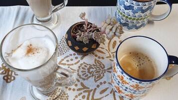 Una mesa con tres vasos de una bebida espumosa, posiblemente café o té, y dos tazas estampadas.