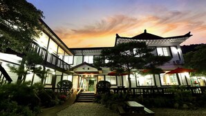 A traditional Japanese-style building with a covered entrance, outdoor seating, and a garden area.