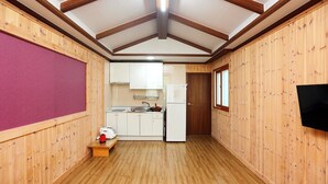 A compact kitchen with wooden walls, a wooden floor, and a ceiling with exposed beams.