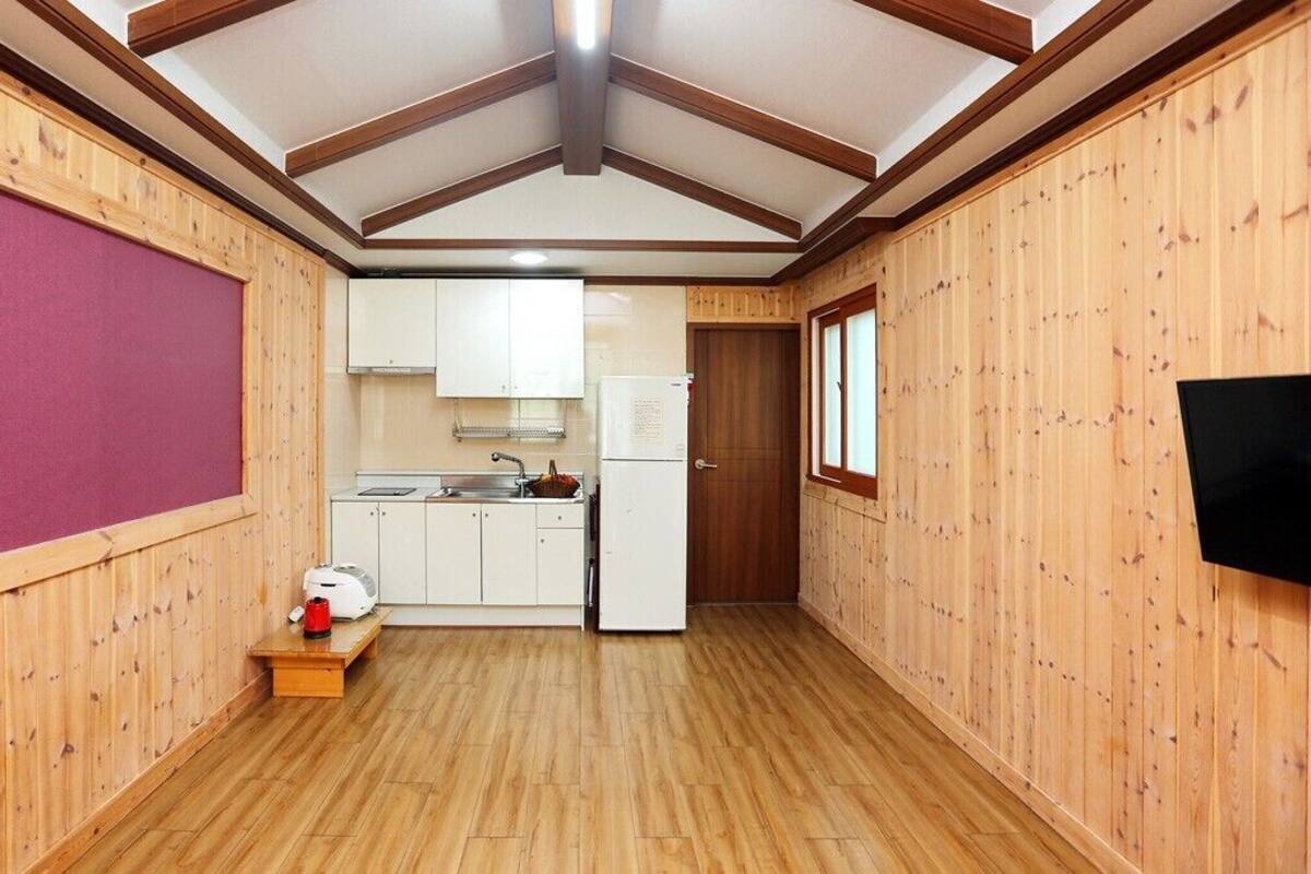 A compact kitchen with wooden walls, a wooden floor, and a ceiling with exposed beams.