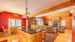 A spacious living area with a wooden floor, a large island with a black countertop, and a fireplace.