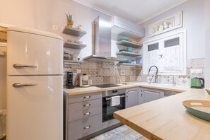 A modern kitchen with a refrigerator, oven, sink, and wooden countertop.