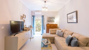 Uma sala de estar moderna com uma TV de tela plana, um sofá, uma mesa de centro e vista para o exterior através de uma janela grande.