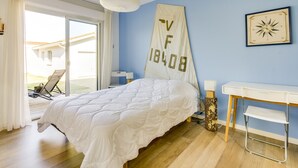 A bedroom with a bed, a desk, a chair, a lamp, and a wall-mounted compass. - Modern Home with Terrace in Biscarrosse – Sleeps 7 with WiFi & BBQ (Biscarrosse)