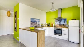 A modern kitchen with a wooden island, white cabinets, a stainless steel sink, and a built-in oven. - Modern Home with Terrace in Biscarrosse – Sleeps 7 with WiFi & BBQ (Biscarrosse)