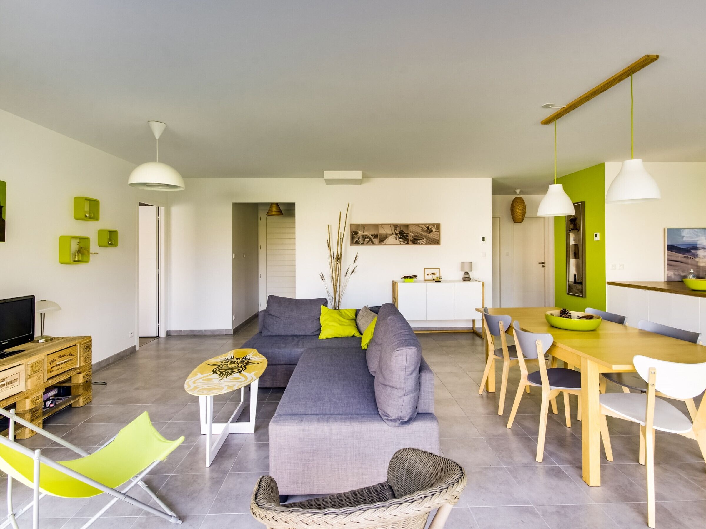 Un salon moderne avec un canapé, une table à manger et des chaises. On y trouve également un téléviseur et une petite table avec une lampe.