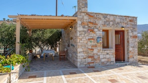 A stone building with a wooden door and a small porch area. - Armonia Studios and Villas (Naxos)