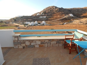 A terrace with stone walls, a blue railing, and a table with chairs. - Armonia Studios and Villas (Naxos)