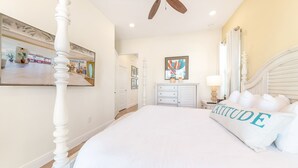 Un dormitorio con cama con dosel, ventilador de techo, espejo grande y vista al exterior.