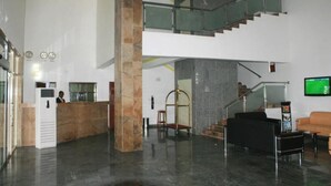 Um hall moderno com balcão de recepção, escada e área de estar.