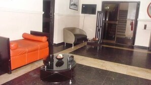 Una sala de estar moderna con una mesa de centro negra, un sofá naranja y un sillón gris.