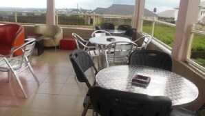 Un balcón con una mesa y sillas, una silla roja, y vista panorámica de la ciudad.