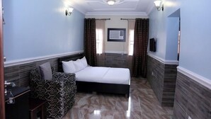 Une chambre à coucher avec un lit, un canapé, une télévision et une fenêtre avec des rideaux.