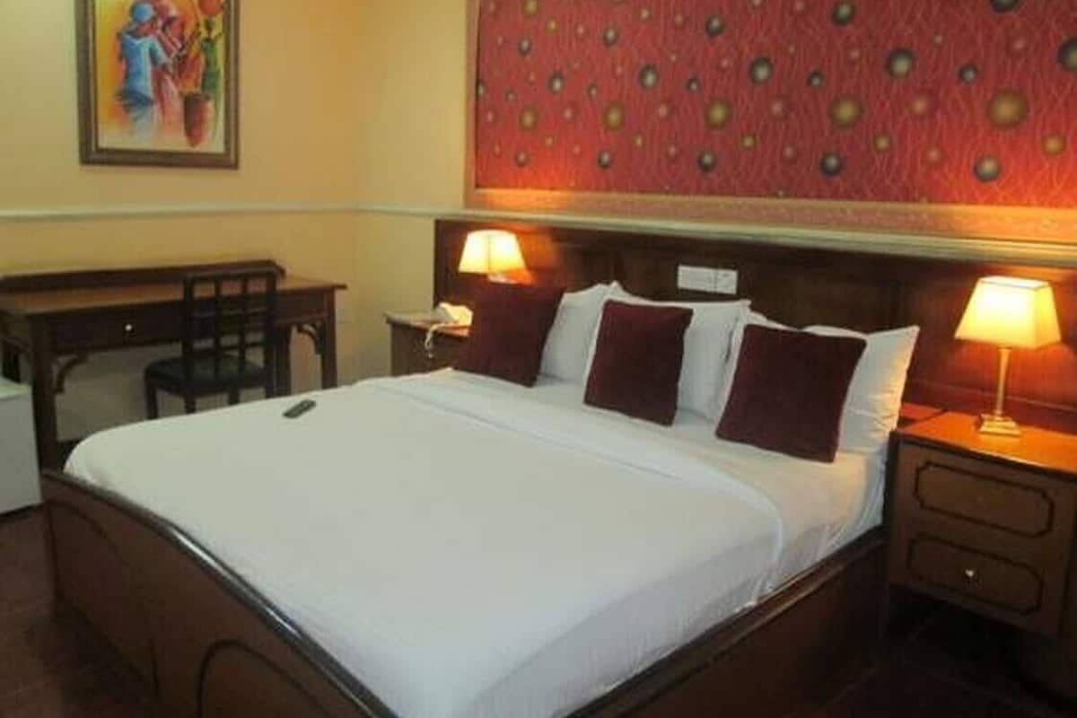 A hotel room with a bed, bedside tables, a desk, and a chair.
