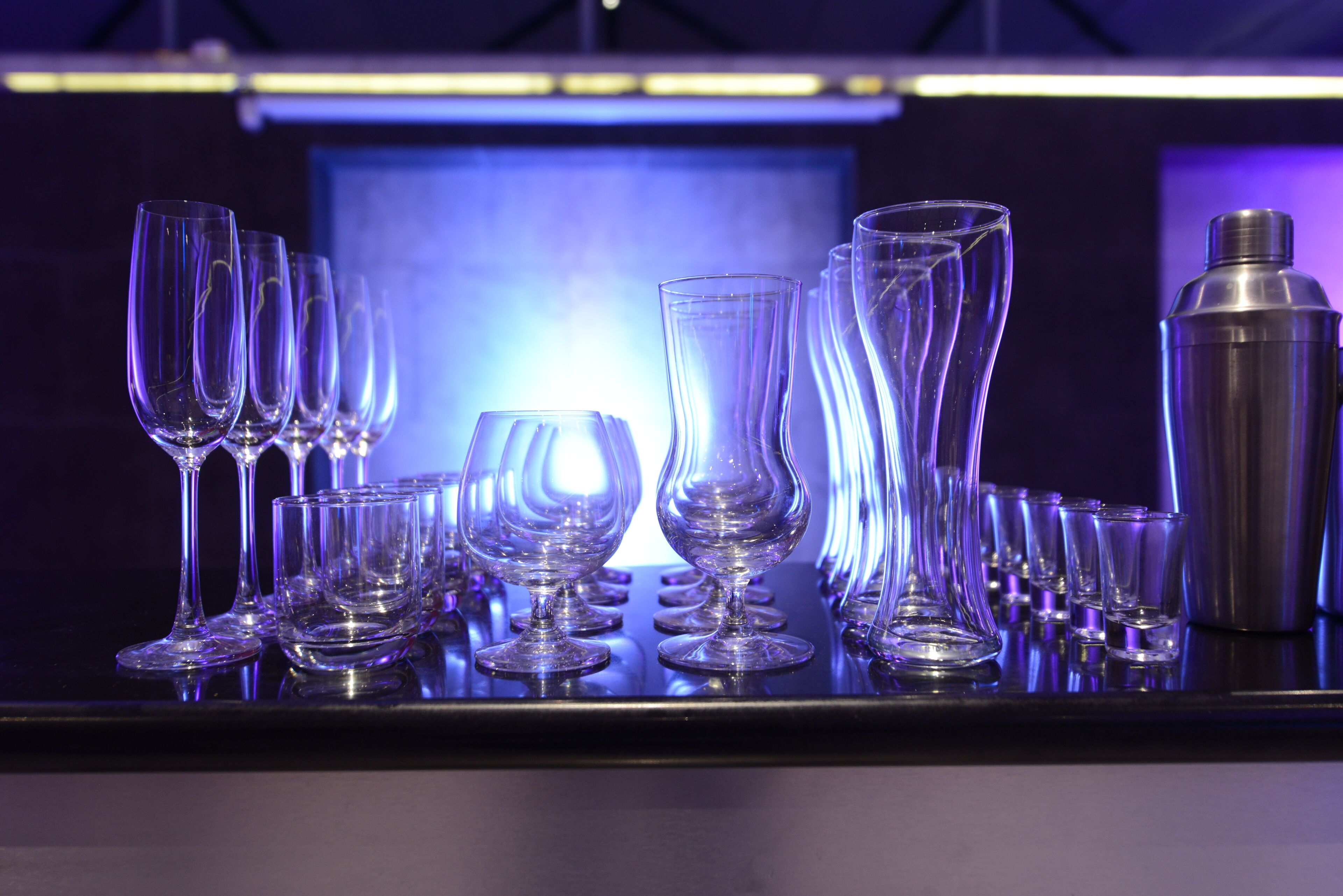 A bar area with various glasses and a cocktail shaker.