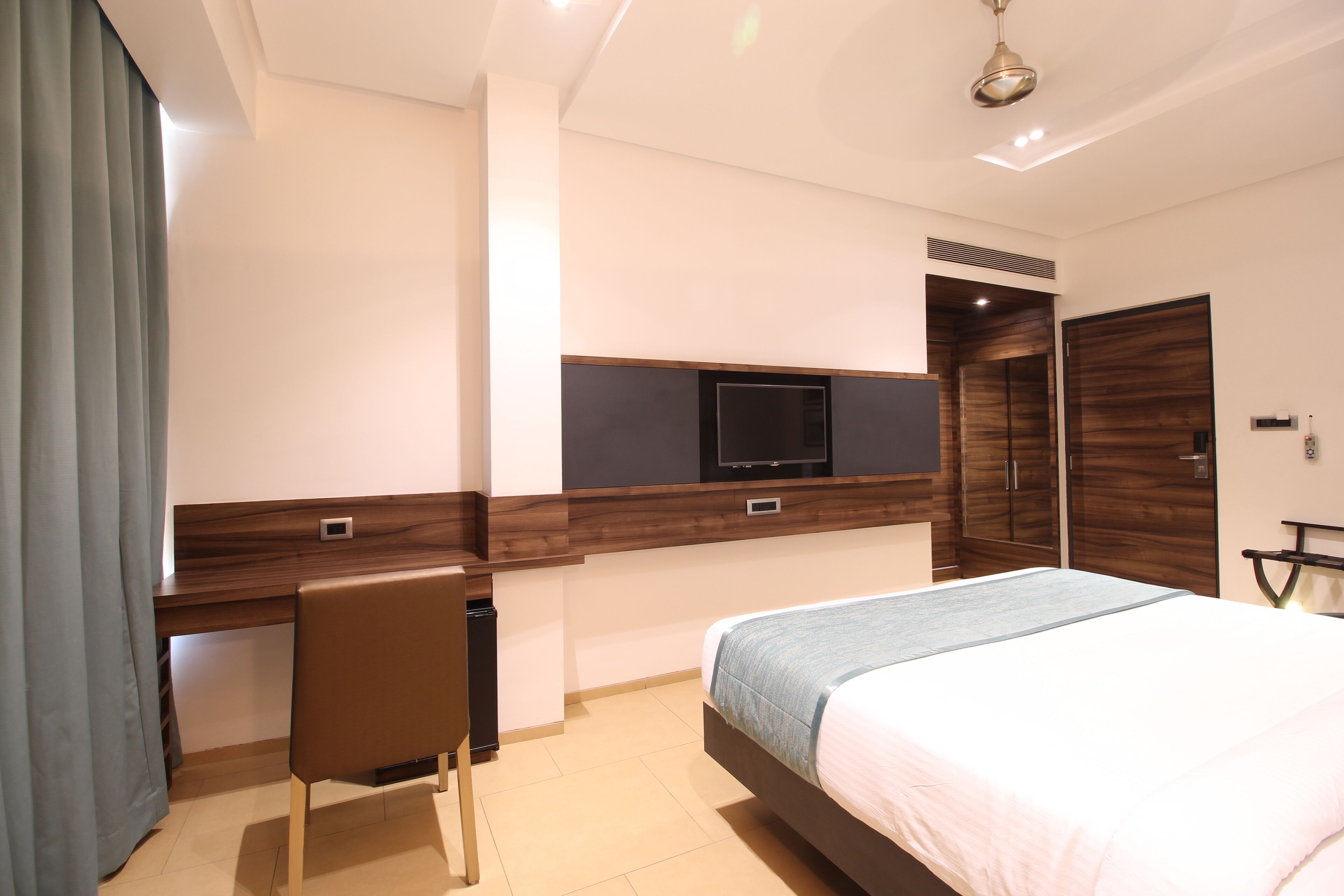 A modern bedroom with a bed, a desk, and a TV.