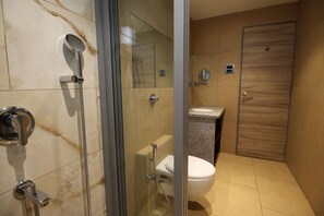 A modern bathroom with a glass-enclosed shower, a toilet, and a sink.