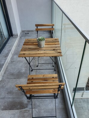 A wooden table and bench set on a balcony with a potted plant. - Srecko No1 Apartment (Belgrade)