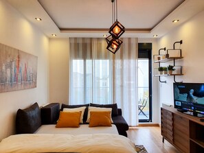 A modern bedroom with a large bed, a TV, and a cityscape painting on the wall. - Srecko No1 Apartment (Belgrade)