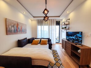 A modern hotel room with a large bed, a TV, a desk, and a cityscape painting on the wall. - Srecko No1 Apartment (Belgrade)