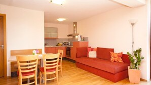 A compact living space with a dining area, kitchenette, and a red sofa. - Gasthof Stern (Vandans)