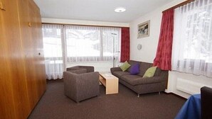 A living room with a sofa, a small table, and a wooden wardrobe. - Haus Aida (Saas-Fee)
