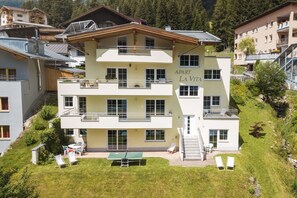 A multi-story building with balconies, a tennis court, and outdoor seating. - Apart La Vita (Sankt Anton am Arlberg)