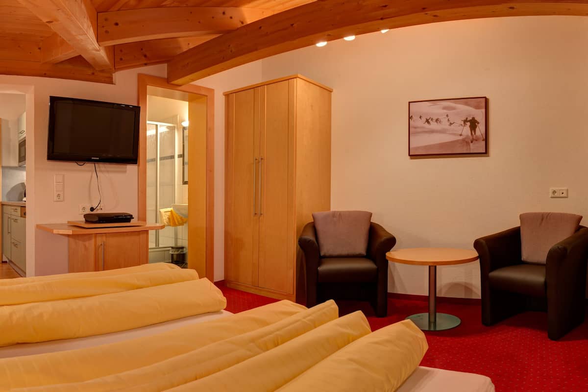 A hotel room with a bed, two armchairs, a small table, a TV, and a picture on the wall.