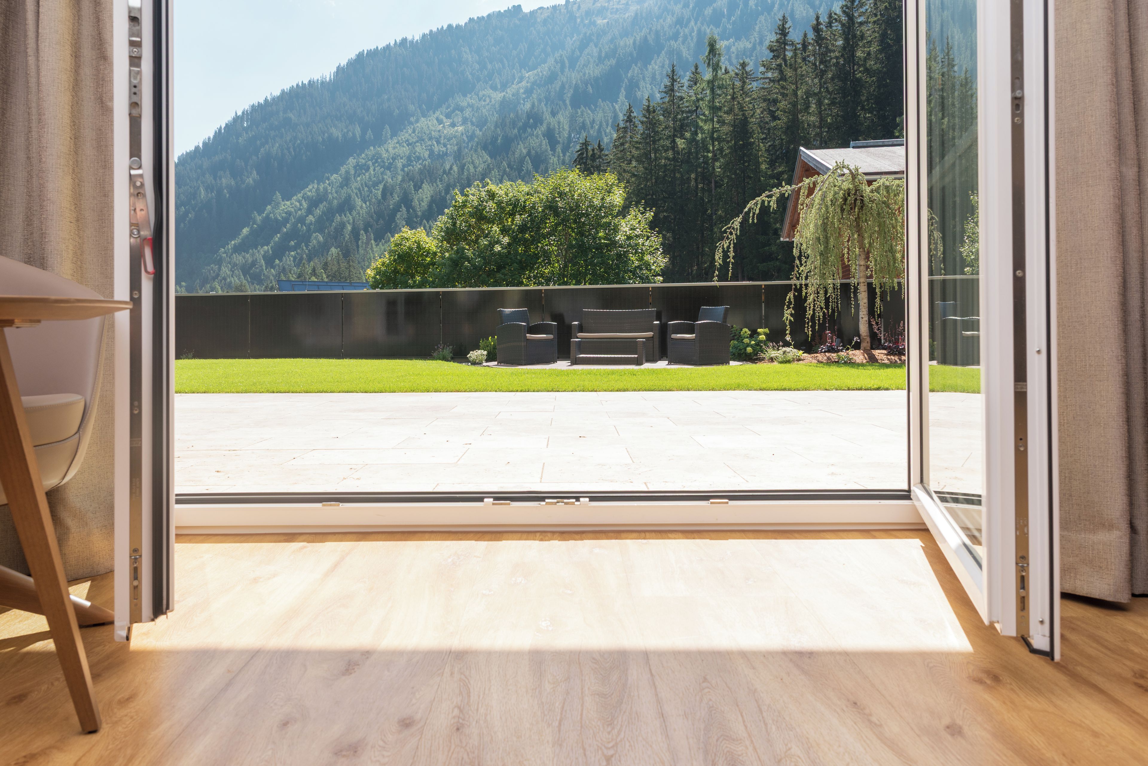 A room with a sliding glass door leading to a balcony with a view of a forested hillside.
