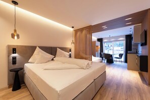 A modern bedroom with a large bed, bedside tables, and a view into the living area. - Apart La Vita (Sankt Anton am Arlberg)