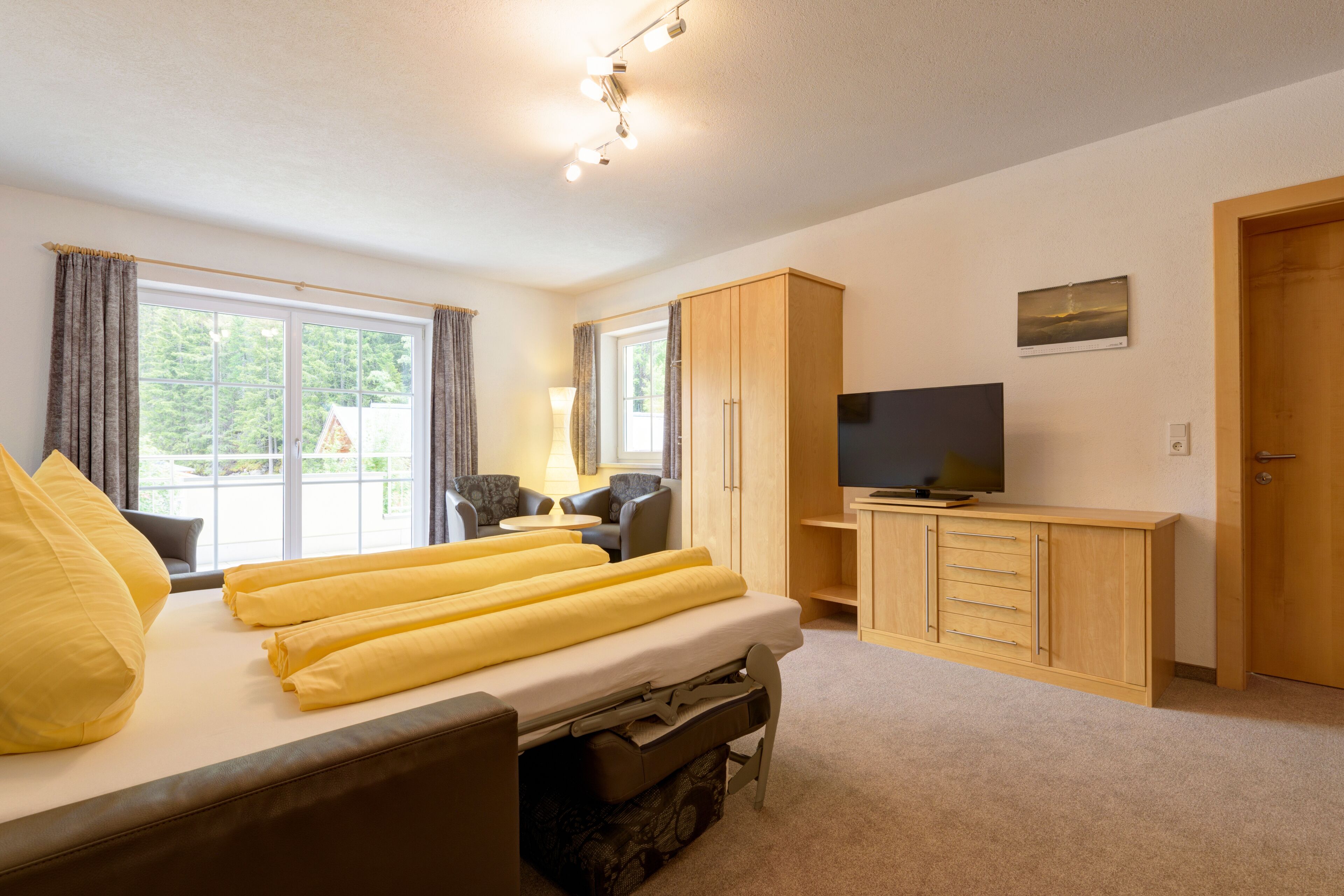 A hotel room with a bed, a television, a wardrobe, and a desk.