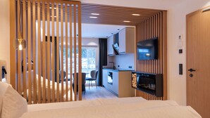 Habitació d'hotel moderna amb un llit gran, un escriptori i una televisió.